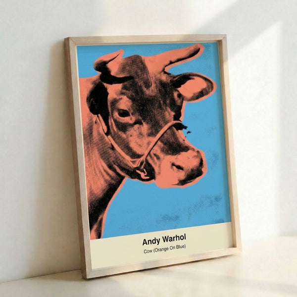 Contemporary pop art wall print of a cow head rendered in saturated orange, blue, and neon yellow-green tones with playful, ironic aesthetic.