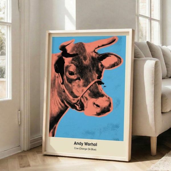 Vibrant pop art cow portrait in orange and blue hues with bright accents, framed as a bold statement art print for modern interiors.