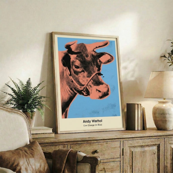 Framed pop art poster showcasing a cow head in striking orange and electric blue palette with high-contrast graphic style.