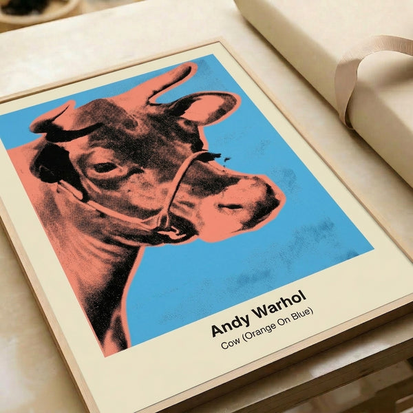 Pop art cow print in saturated orange, blue, and yellow-green on wall, featuring bold graphic design with subversive, playful mood.