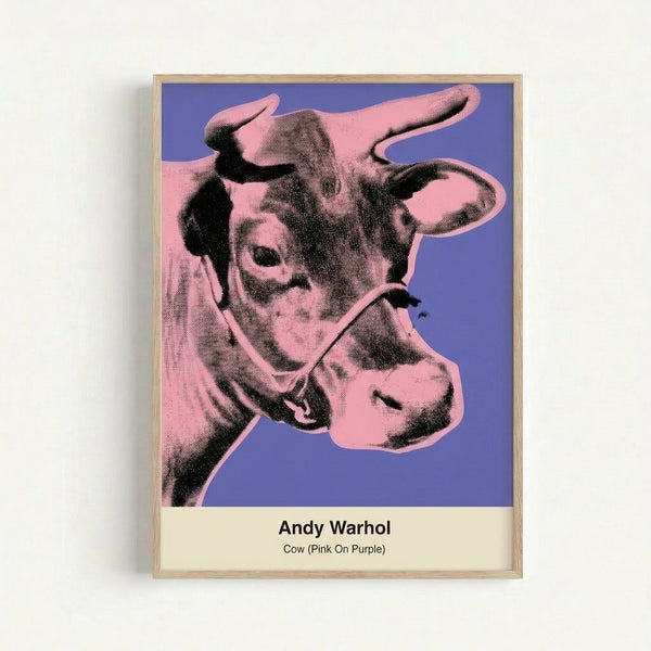 Framed pop art print displaying a stylized cow portrait in bright pink tones on purple, evoking kitsch and irreverent contemporary aesthetics.
