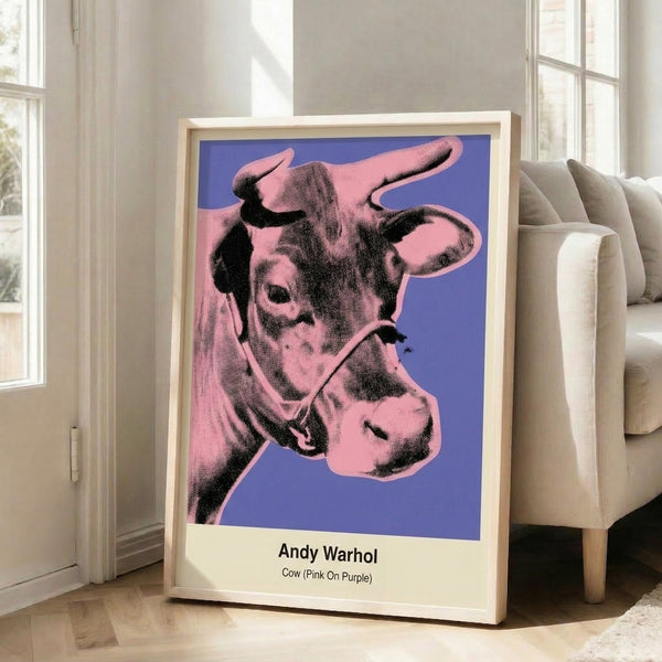 Framed modern art print of a cow head in pop art style, featuring striking pink coloring and bold graphic lines on a purple field.