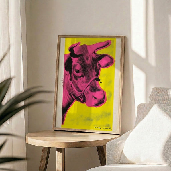 Kitsch-inspired framed print with a striking pink bovine head design floating on a cheerful yellow field.