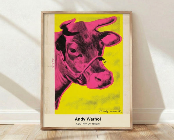 Bold pop art poster featuring a pink cow head against a vibrant yellow background with black outlines, displayed as a framed print on a wall.