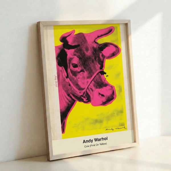 Pop art cow head rendered in hot pink with black contours on a sunny yellow background, mounted as a contemporary wall poster.