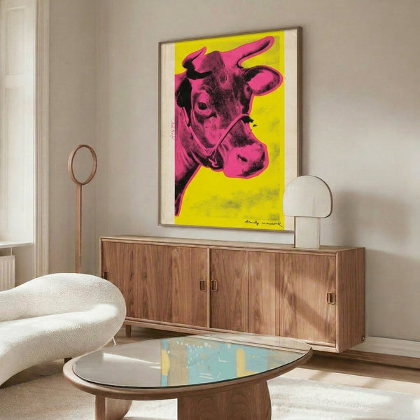 Framed pop art poster featuring a playful pink cow with black outlines on vivid yellow, exemplifying modern kitsch and bold graphic design.