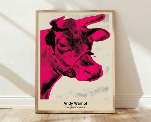 Bold pop art poster of a red and white cow head against a white background, modern Bauhaus-inspired design framed on a wall.