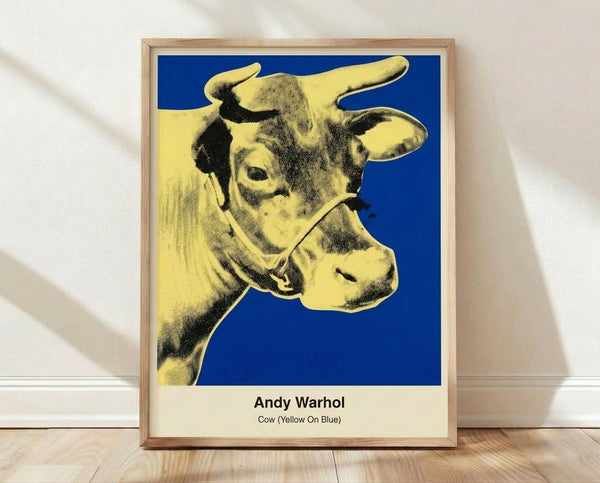 Bold pop art poster featuring a stylized cow head in bright yellow and magenta against a vibrant blue background, exemplifying Warhol's iconic high-contrast printmaking style.