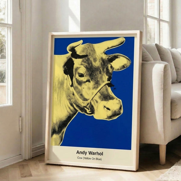 Pop art cow portrait in bright yellow and pink hues set against saturated blue, a playful modern interpretation of farm imagery through bold commercial art aesthetics.