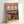 Wall art depicting a quaint bookstore entrance with sage green plants, cream-colored trim, and warm brick in a minimalist japandi style that feels inviting and literary.