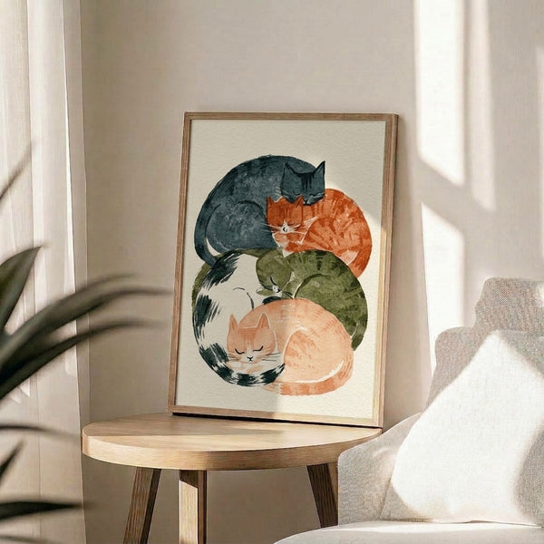 Cozy minimalist watercolor artwork featuring a peaceful pile of cats in muted earth tones and charcoal accents, displayed as a framed art print.