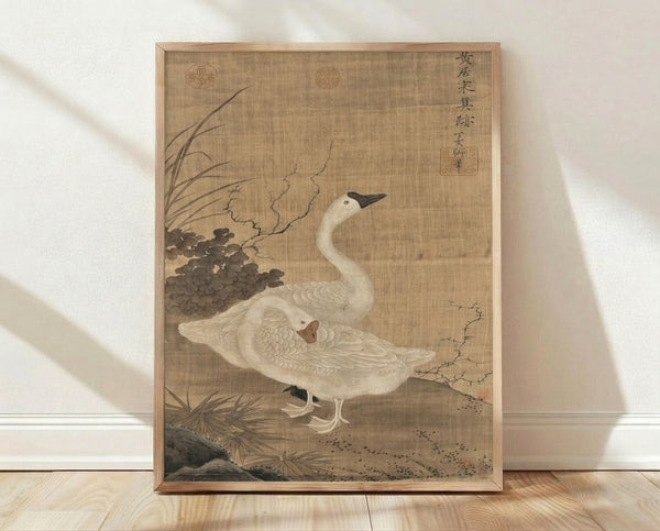 Framed Japanese woodblock print of two cranes among reeds and vegetation in muted cream, beige, and brown tones, evoking serene Edo period naturalism.