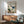Zen-inspired wall poster showing a wading crane in a minimalist misty mountain wetland scene, combining soft greens, charcoal strokes, and subtle coral-orange details in a meditative composition.
