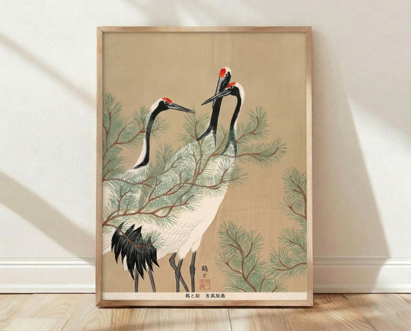 Serene Japanese woodblock print featuring a crane perched on a pine branch, rendered in cream, black, and muted green tones with red accents, framed on a wall.