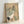 Auspicious crane and pine woodblock artwork in muted cream and black with subtle red and green, displayed as a framed poster with zen garden aesthetic.