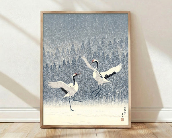 Serene Japanese woodblock-style poster featuring two cranes in falling snow amid winter forest, rendered in slate blue, cream white, and navy tones with red accent details.