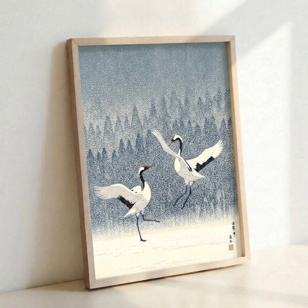 Peaceful framed art print showing cranes in a snowy woodland scene, executed in Japanese woodblock technique with muted palette of slate blue, white, and dark navy.