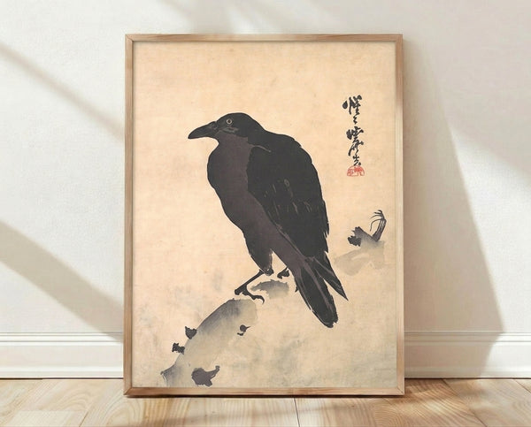 Framed Japanese minimalist ink wash painting of a crow perched on a rock, rendered in black and charcoal tones against a cream background.