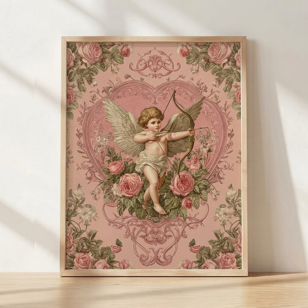 Vintage Art Nouveau framed poster featuring a romantic cupid with bow and arrow surrounded by dusty rose flowers and a heart, rendered in soft pink, sage green, and cream tones.