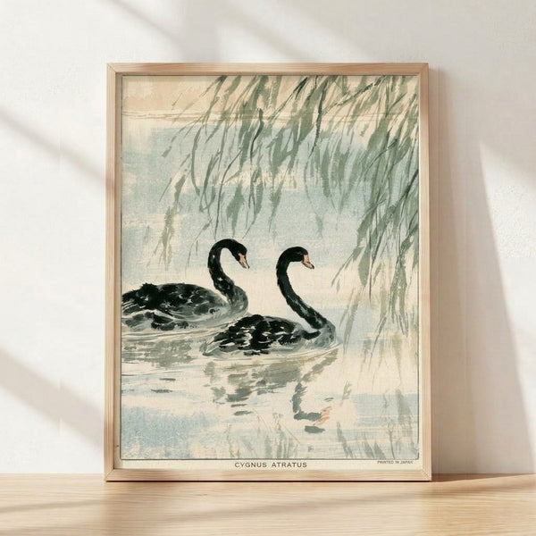 Serene framed poster of a black swan gliding near a willow tree and water lilies, rendered in Japanese woodblock style with sage green, cream, and pale blue tones creating a contemplative Japandi aesthetic.
