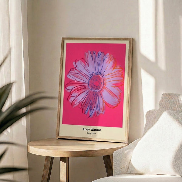 Framed artistic print featuring a stylized daisy in luminous pink and magenta tones with yellow center detail, embodying bold pop art sensibility and contemporary floral design.