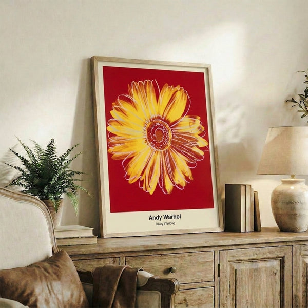 Vibrant pop art floral print showing a simplified daisy form in bright yellow, green, and pink hues on neutral background, framed on wall.