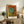 Framed Impressionist artwork of dancers stretching at the barre in soft cream and ochre tones, evoking a contemplative moment in the ballet studio.