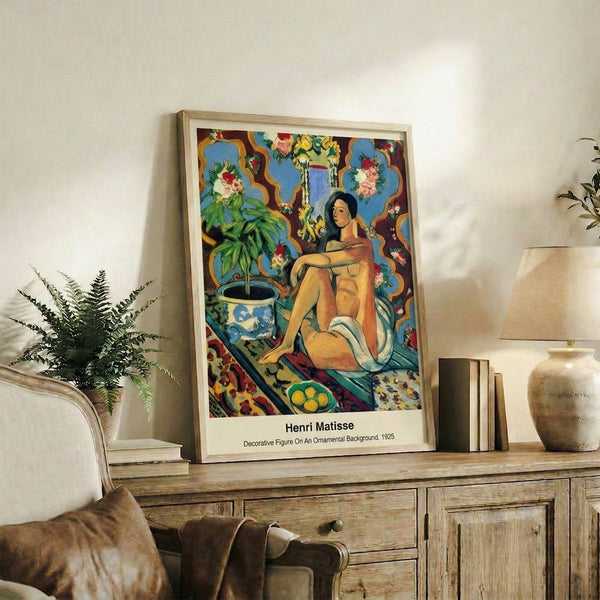 Matisse-style decorative figure print with exotic interior setting, patterned fabrics, and sophisticated color blocking in ochre, burgundy, teal, and cream displayed on wall.