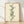 Watercolor botanical wall art depicting a delicate DNA helix intertwined with rose vines and leaves in soft peach, sage, and cream tones, framed on a wall.