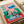 Contemporary line art print of whimsical greyhounds and a black cat in a comfortable interior, with one dog absorbed in reading a newspaper, accented with red, blue, and cream colors.