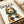 Minimalist modern poster showcasing a sophisticated dogue in trendy sunglasses and pearl necklace with headscarf, illustrated in cream, tan, and forest green.