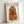 Friendly illustrated dogue poodle sporting chic eyeglasses and a tied headscarf, blending watercolor washes with line art details in a palette of orange, gold, and brown tones.