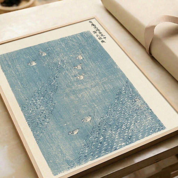 Framed traditional Japanese woodblock poster showing birds in flowing stream, charcoal and pale blue palette evoking serene, peaceful mood.