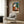 Whimsical surrealist interior scene reimagined through geometric abstraction, featuring warm ochre and rust tones with bold black accents on a cream-colored art print.