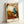 Dreamlike abstract interior scene with playful distorted furniture and objects in rust and cream hues accented by teal, rendered in surreal artistic style as wall art.
