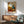 Whimsical surreal abstract art print featuring interior and furniture-inspired forms in warm ochre and rust with cool teal accents, displayed as framed poster.