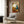 Framed abstract print featuring dreamlike biomorphic shapes and linear marks in warm beige, ochre, and charcoal creating a playful surrealist interior.