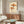 Japanese-inspired woodblock print depicting imaginative umbrella yokai and bird companions in a lighthearted composition, displayed as wall art in cream and terracotta tones.