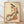 Framed Japanese woodblock print depicting an elegant woman in an ornate kimono with flowing fabric, adorned with coral and olive green floral motifs against a cream background.