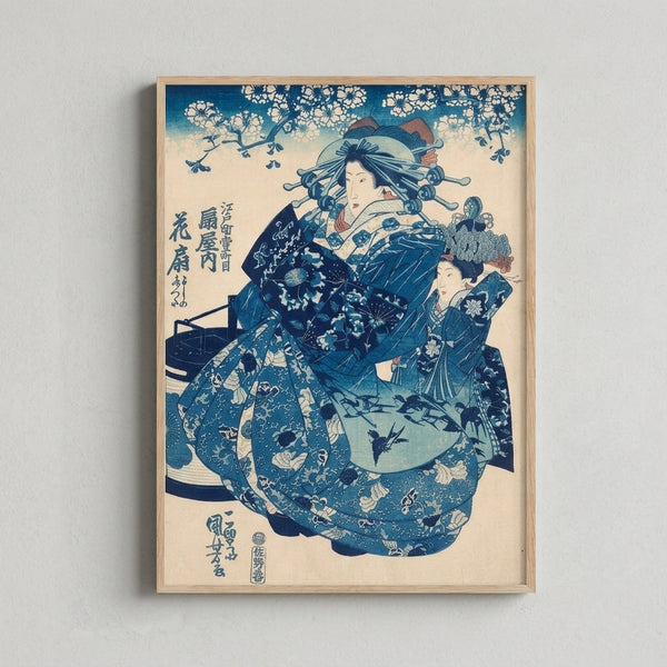 Vintage-style framed Japanese woodblock art depicting a serene geisha figure in soft teal and indigo hues, adorned with a fan and delicate floral motifs.