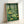 Modern linocut-style poster of an enchanted mushroom woodland in dark teal and sage green with a serene, magical mood.