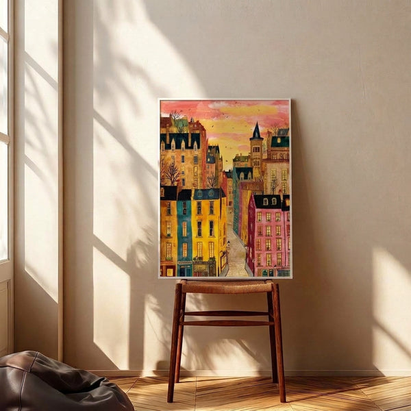 Whimsical watercolor illustration of an old-world city street with ornate buildings in warm ochres and pinks, a distant castle tower, and flying birds set against a golden sky, matted and framed.