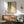 Contemporary abstract artwork displaying organic falling dots in earthy greens and coral hues with golden accents, conveying peaceful movement and natural flow.