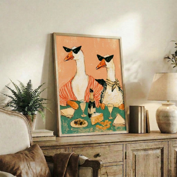 Framed poster art in retro style depicting a chic goose at a wine party with sunglasses, cheese, and crackers in a whimsical palette of tan, cream, and forest green.