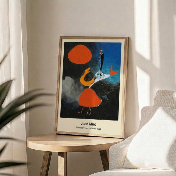 Framed surrealist print with a stylized female figure rendered in black and crimson reaching toward or confronting a brilliant yellow solar form, set against cream.