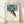 Whimsical retro folk art poster of a teal blue heron wearing a colorful party hat against a night sky with golden sun, moon, and stars in cream and black.