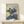Framed art print of a distorted figure at a desk, mirrored composition in subdued palette of browns and blacks, evoking introspection and psychological depth.