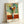 Contemporary botanical wall art depicting a striking arrangement of flowers in rich magenta, orange, and green hues with bold abstract composition.
