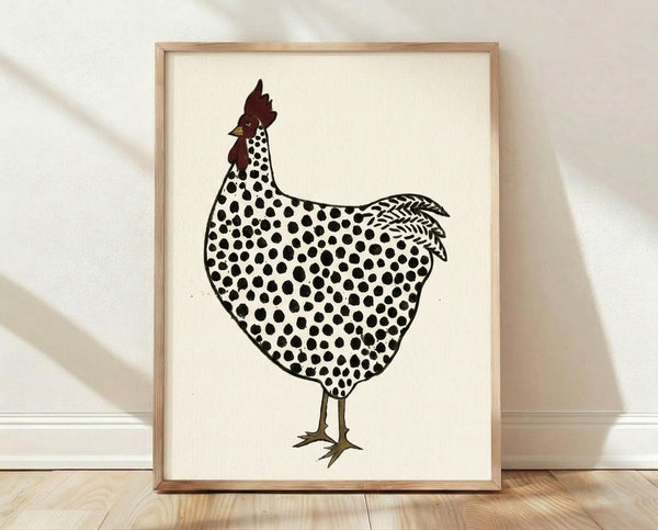 Charming folk art print of a polka dot rooster in cream, black, and dark red, displayed as a framed linocut-style poster on a wall.