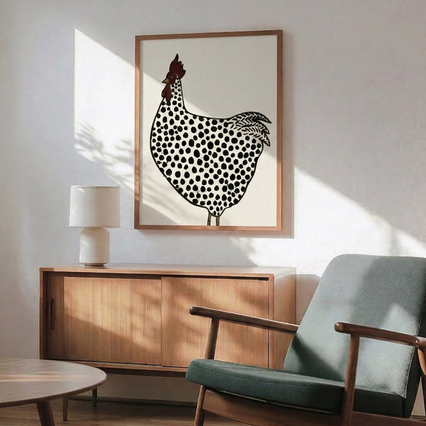 Framed farmhouse print of a whimsical dotted chicken in traditional folk art style, featuring warm ochre and cream palette with striking black linework.